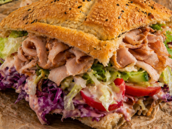 Bamberger Metzgerei Böhnlein verkauft fränkischen Döner - mit Leberkäse Ein Dönersandwich mit knusprigem Sesambrot, gefüllt mit Fleisch, Rotkohl, Salat und Tomaten, angerichtet auf Papier. Es ist die fränkische Version eines Döner-Imbiss-Klassikers.