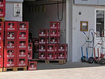 "Alles wird geschlossen": Fränkische Traditionsbrauerei muss schließen - nach über 150 Jahren Im Bild sind gestapelte Bierkästen der Familienbrauerei Hennemann vor einem Gebäude zu sehen. Daneben stehen Handwagen. Die Brauerei ist in Sambach ansässig.